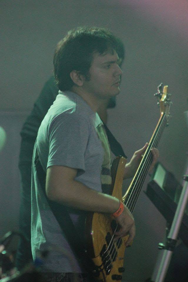 Diego Volpatto tocando contrabaixo no palco, sob iluminação verde.